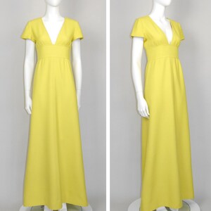 May include: A bright yellow maxi dress with a V-neckline and short sleeves. The dress features a fitted bodice and a flowing skirt. The dress is displayed on a mannequin. The dress is a solid color and appears to be made of a lightweight fabric.