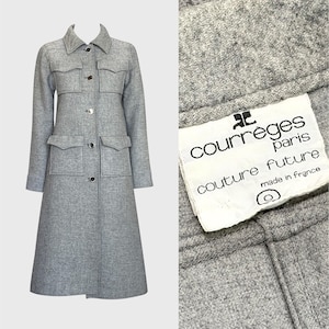 Puede incluir: Un abrigo de lana gris claro con un diseño clásico. El abrigo presenta un cuello, cuatro bolsillos delanteros y cierres de botón. La etiqueta dice "Courrèges Paris Couture Future made in France."