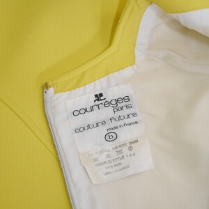 May include: Close-up of a bright yellow garment with a white lining and a zipper. A tag inside the garment reads "courr&egrave;ges paris couture future made in france". The tag also lists fabric content as 100% wool and 100% polyamide.