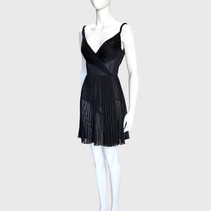 K&ouml;nnte beinhalten: Ein schwarzes Kleid auf einer Schaufensterpuppe. Das Kleid hat ein V-Ausschnitt-Oberteil mit Wickeldesign und d&uuml;nnen Tr&auml;gern. Der Rock ist plissiert und reicht bis zur Mitte des Oberschenkels. Das Kleid ist aus einem transparenten Stoff gefertigt.