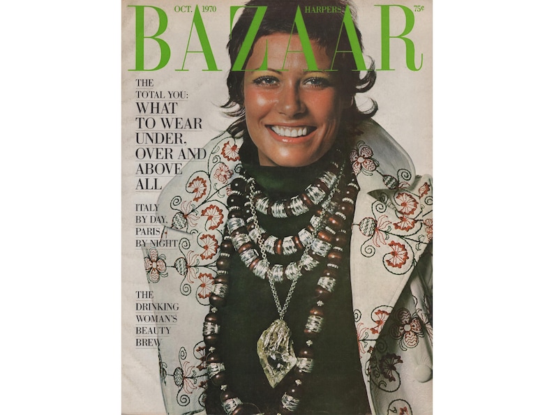 May include: October 1970 Harper's Bazaar magazine cover featuring a smiling woman. She wears a dark green top, layered beaded necklaces, and a jacket with floral embroidery. The magazine title is in green.