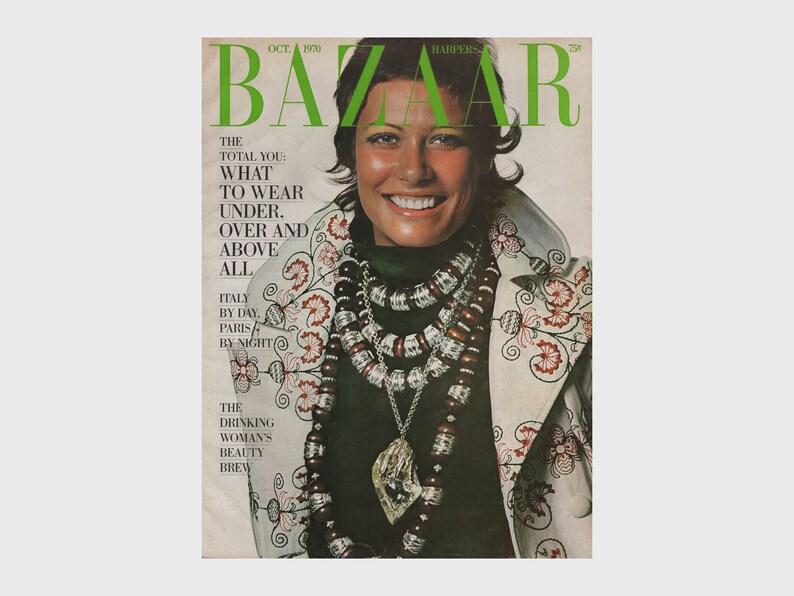 May include: October 1970 Harper's Bazaar magazine cover featuring a smiling woman wearing a green top and a white jacket with floral embroidery. She is adorned with layered necklaces and a pendant. The magazine title is in green.