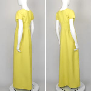 May include: A bright yellow, floor-length dress with short sleeves and a fitted waist. The dress is displayed on a mannequin, showcasing its simple, elegant design. The dress has a round neckline and a subtle A-line skirt.