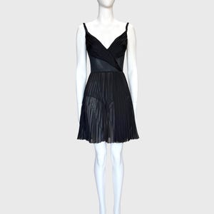 K&ouml;nnte beinhalten: Ein schwarzes Kleid auf einer Schaufensterpuppe. Das Kleid hat ein V-Ausschnitt-Oberteil mit Spaghettitr&auml;gern und einen plissierten Rock. Das Oberteil scheint aus einem strukturierten Stoff zu sein, w&auml;hrend der Rock ein durchsichtiges, flie&szlig;endes Material ist.