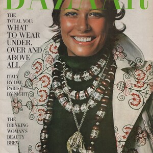 May include: October 1970 cover of Harper's Bazaar magazine. The cover features a smiling woman wearing a dark green top and a white jacket with red floral embroidery. She is adorned with layered necklaces and a large pendant.