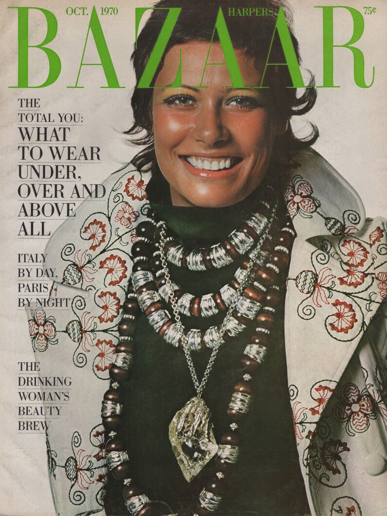 May include: October 1970 cover of Harper's Bazaar magazine. The cover features a smiling woman wearing a dark green top and a white jacket with red floral embroidery. She is adorned with layered necklaces and a large pendant.