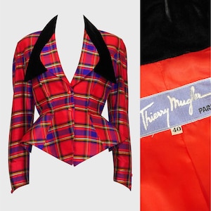 May include: A vintage red, blue, and yellow plaid blazer with black velvet lapels. The blazer has a fitted waist and button closure. The lining is bright red, and a label reads "Thierry Mugler PARIS".