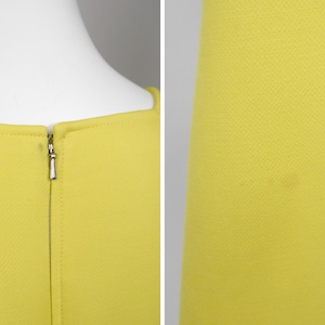 May include: Close-up of a bright yellow dress. The dress features a square neckline and a silver zipper closure at the back. The fabric has a subtle textured pattern. The dress is displayed on a white mannequin.