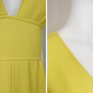 May include: Close-up of a bright yellow dress with a plunging neckline. The dress features a fitted bodice and a defined waistline. The fabric appears to be a textured knit, and the seams are neatly stitched.