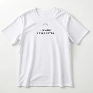 Op de afbeelding: Een wit t-shirt met korte mouwen en een zwarte afbeelding op de borst. De afbeelding bevat een klein zonicoon boven de tekst "Mascara" in een schreeflettertype, gevolgd door de woorden "COULD NEVER" in een vet, schreefloos lettertype.