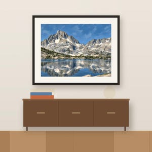 Thousand Island Lake gouache-style print in a dark frame above a wooden sideboard, shown as a room mockup