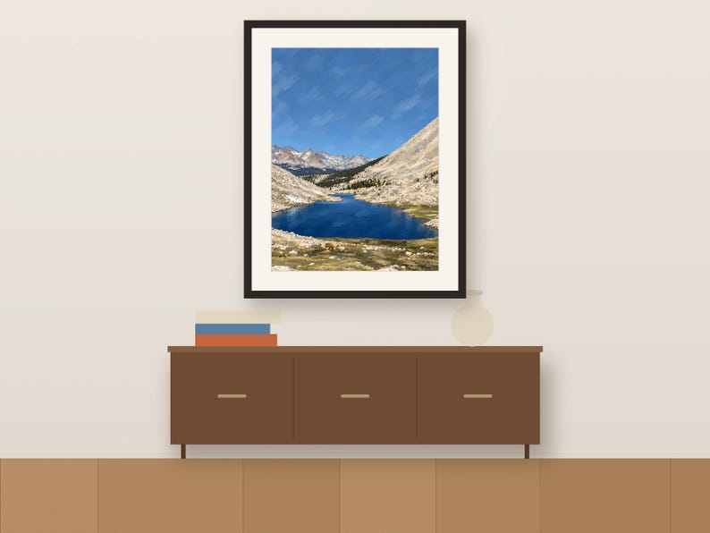 Guitar Lake gouache-style vertical print in a dark frame above a wooden sideboard, shown as a room mockup