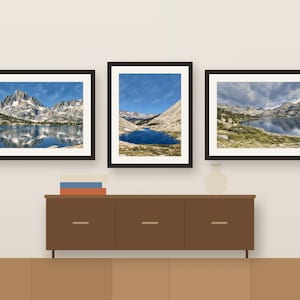 Three framed Sierra lake prints in a row above a wooden sideboard, shown as a room mockup
