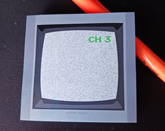 Può includere: Un adesivo grigio e nero con uno schermo televisivo retrò che mostra rumore statico. Lo schermo mostra il testo "CH 3" in verde.