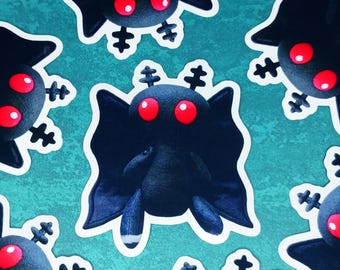 Può includere: Un motivo di peluche neri a forma di pipistrello con occhi rossi e contorni bianchi. I giocattoli hanno un design a cartoni animati con piedini e un'espressione sorridente. Lo sfondo è di colore verde acqua.