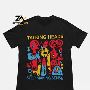 May include: A black short-sleeve t-shirt featuring a graphic print with the text TALKING HEADS and STOP MAKING SENSE. The design includes abstract figures and shapes in red, yellow, and blue colors. The logo zaynmallik Art is visible.