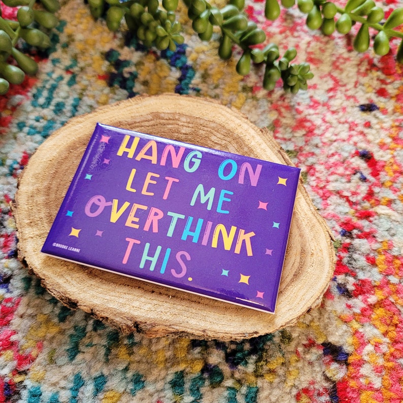 Op de afbeelding: Paarse vierkante magneet met de tekst "HANG ON LET ME OVERTHINK THIS." in kleurrijke letters met witte sterren rond de tekst.