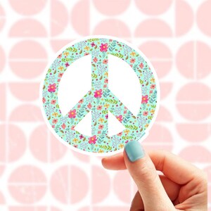 A peace sign with a floral pattern on a light blue background. The flowers are pink, yellow, and orange. The background is white with pastel coloured brushstrokes.