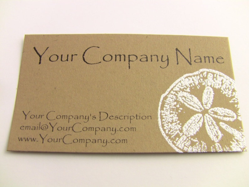Pu&ograve; includere: Un biglietto da visita in carta marrone con inchiostro bianco. Il biglietto presenta il testo "Your Company Name" in alto e "Your Company's Description" in basso. Il biglietto presenta anche un'immagine bianca di un dollaro di sabbia nell'angolo in basso a destra. Il testo "email@YourCompany.com" e "www.YourCompany.com" &egrave; stampato sotto la descrizione dell'azienda.