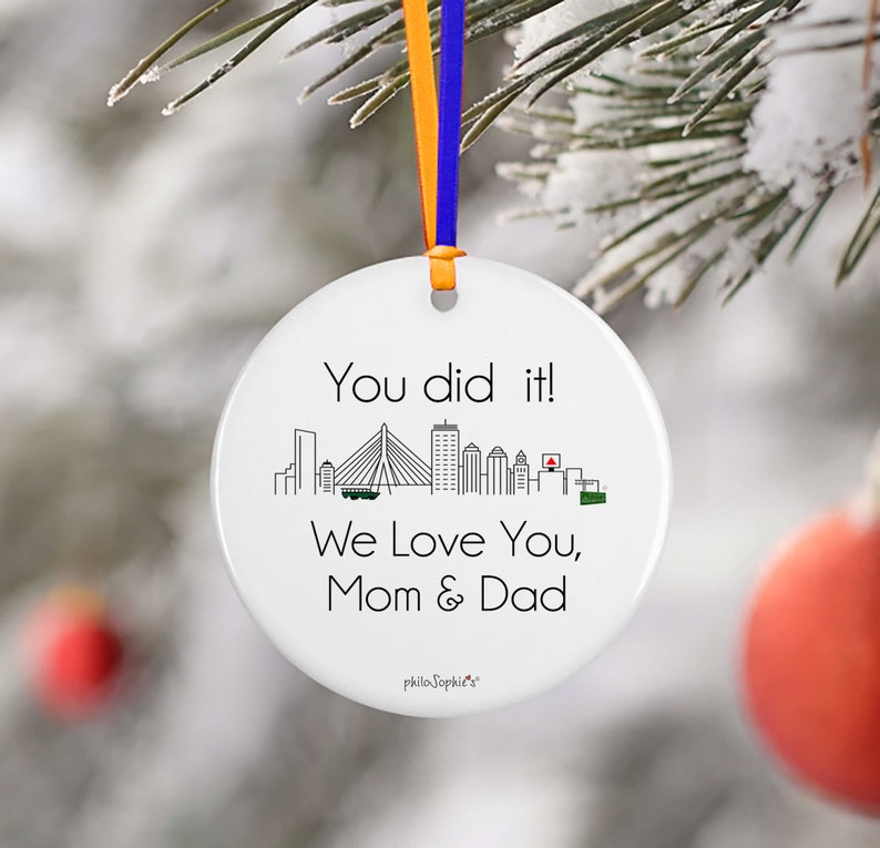May include: White ceramic bauble with a black outline of a city skyline and the text "You did it! We love you, Mom & Dad".