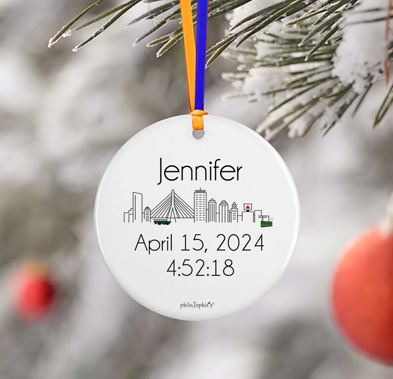 May include: White ceramic bauble featuring a black and white cityscape silhouette, the name "Jennifer", the date "April 15, 2024", and the time "4:52:18".