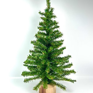 May include: A small, artificial Christmas tree with vibrant green needles. The tree is mounted on a natural wood base. The tree's branches are evenly spaced, creating a full, conical shape. Perfect for holiday decor.