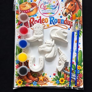 Pode incluir: Um kit de artesanato Rodeo Roundup em embalagem transparente com uma bota de cowboy, chapéu, cabeça de cavalo, ferradura e revólver em cerâmica branca. Inclui cinco potes de tinta e dois pincéis para pintura.