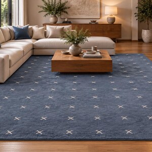 Könnte beinhalten: Ein großer rechteckiger Teppich in einem tiefen Blauton mit einem sich wiederholenden Muster aus kleinen weißen Kreuzsymbolen in einem Raster. Der Teppich hat eine kurzflorige Textur und bedeckt einen großen Teil des Holzbodens.
