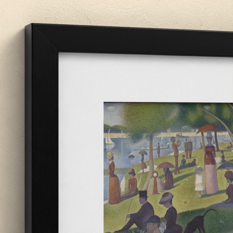 May include: A framed art print featuring a pointillist painting of a park scene by a river. The artwork depicts numerous figures in period clothing, including hats and dresses, relaxing on a grassy bank with sailboats visible on the water.