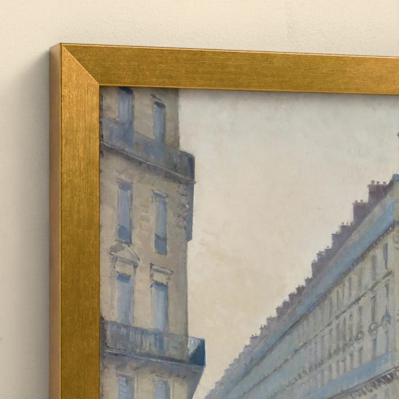 May include: A framed painting depicting a city street scene with tall, light-colored buildings featuring blue-tinted windows and balconies. The artwork is enclosed in a textured, metallic gold frame that borders the top and left edges.