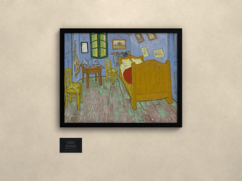 May include: A framed print of Vincent van Gogh's Bedroom in Arles painting, featuring a yellow bed, two wooden chairs, a small table, and blue walls, displayed with a small black informational plaque below the artwork.