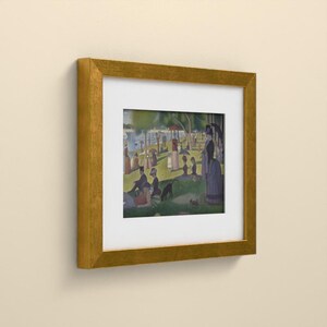 May include: A framed print featuring a pointillist-style painting of a park scene with numerous figures, trees, and a body of water. The artwork is enclosed in a textured gold-colored frame with a wide white mat border surrounding the image.