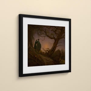 May include: A framed print featuring a dark, atmospheric landscape painting of two figures standing on a rocky path beneath a gnarled, leafless tree. A thin crescent moon glows in the twilight sky above a distant, shadowy forest horizon.