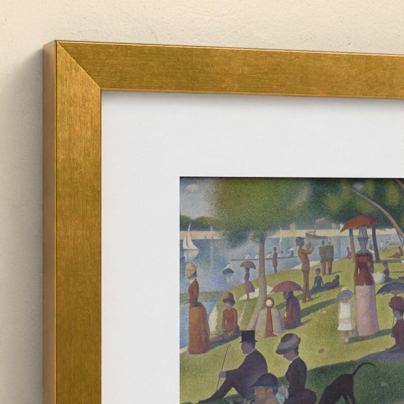 May include: A framed print of Georges Seurat's A Sunday Afternoon on the Island of La Grande Jatte, featuring a pointillist park scene with figures, trees, and a river, enclosed in a textured metallic gold frame with a white mat border.