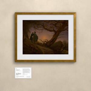 May include: A framed art print of the painting Two Men Contemplating the Moon by Caspar David Friedrich, featuring two figures standing on a rocky path under a gnarled tree, observing a crescent moon in a dark, twilight sky, with a small information card below.