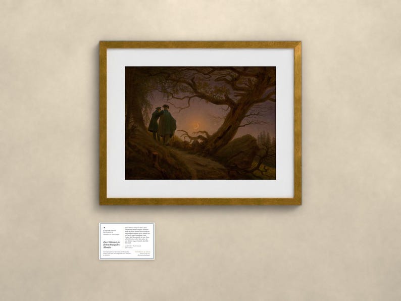 May include: A framed art print of the painting Two Men Contemplating the Moon by Caspar David Friedrich, featuring two figures standing on a rocky path under a gnarled tree, observing a crescent moon in a dark, twilight sky, with a small information card below.