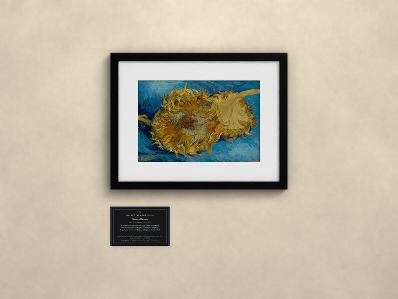 May include: A framed print of Vincent van Gogh's Sunflowers painting, featuring two golden-yellow sunflowers against a textured blue background. Below the black frame is a small rectangular plaque with white text detailing the artwork.