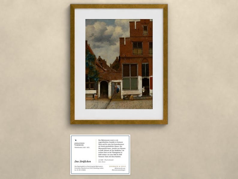 May include: A framed print of Johannes Vermeer's painting The Little Street, featuring red brick houses, a cobblestone path, and a cloudy sky. Below the frame is a white information card with black text detailing the artwork's history.