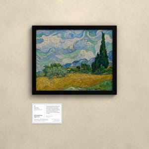 May include: A framed oil painting featuring a golden wheat field under a swirling blue sky with a tall dark green cypress tree on the right. Below the painting is a small white informational placard with black text detailing the artwork.
