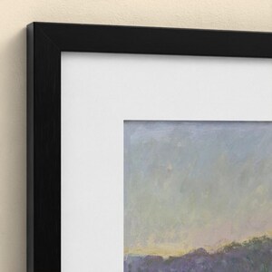 May include: A framed wall art piece featuring a landscape painting with a soft, muted sky above a dark, textured horizon line. The artwork is enclosed in a simple, flat black frame with a wide, clean white mat border surrounding the image.