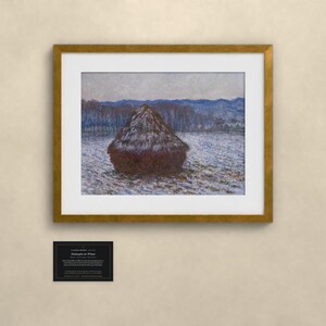 K&ouml;nnte beinhalten: Ein gerahmter Druck von Claude Monets Getreideschober im Winter, der einen dunkelbraunen Heuhaufen auf einem verschneiten Feld mit bl&auml;ulichen B&auml;umen und H&uuml;geln zeigt. Darunter befindet sich eine schwarze Plakette mit wei&szlig;em Text.