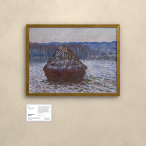 May include: A framed landscape painting featuring a large, dark brown haystack centered in a snowy field under a pale sky. In the background, blue-toned hills and trees are visible. Below the painting is a small white informational card with text.