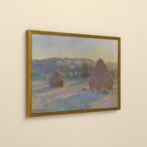May include: A framed landscape painting featuring two large haystacks in a field under a soft, hazy sky. The scene uses a palette of muted purples, blues, and golden yellows, with visible brushstrokes and the signature Claude Monet 91.