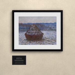 K&ouml;nnte beinhalten: Ein gerahmter Kunstdruck von Claude Monets Getreideschober im Winter, der einen dunkelbraunen Heuhaufen auf einem verschneiten Feld mit blauen H&uuml;geln im Hintergrund zeigt. Das Bild befindet sich in einem schwarzen Rahmen mit wei&szlig;em Passepartout.