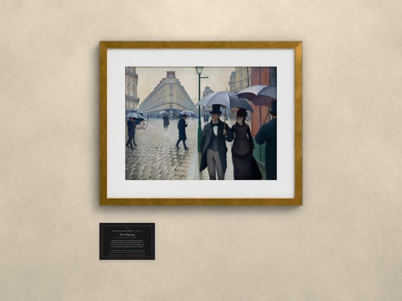 May include: A framed print of the painting Paris Street; Rainy Day, featuring figures in formal attire with umbrellas walking on a cobblestone street. The artwork is displayed in a gold frame with a white mat, accompanied by a small black plaque.