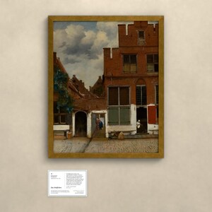 May include: A framed oil painting depicting a Dutch street scene with red brick buildings, a cobblestone path, and a cloudy sky. Below the painting is a small white informational plaque with black text detailing the artwork's history.