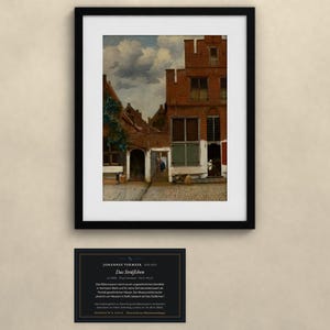 May include: A framed art print of Johannes Vermeer's painting The Little Street, depicting red brick houses and a cobblestone alleyway. Below the frame is a black informational plaque with white text detailing the artwork and artist.