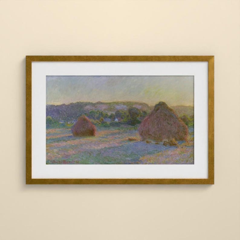 May include: A framed landscape painting featuring two large haystacks in a field under a soft sky. The artwork uses a palette of muted purples, blues, and golden yellows to depict the scene, enclosed in a metallic gold frame with a white mat.