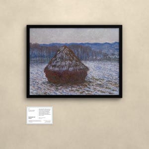 May include: A framed landscape painting featuring a large, dark brown haystack centered in a snow-covered field. In the background, a line of bare trees sits before blue, rolling hills under a pale sky. A small white informational plaque is below.