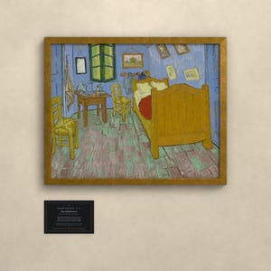 May include: A framed print of Vincent van Gogh's Bedroom in Arles painting, featuring a yellow bed, two wooden chairs, and a small table in a blue room. Below the artwork is a black rectangular plaque with white text detailing the piece.